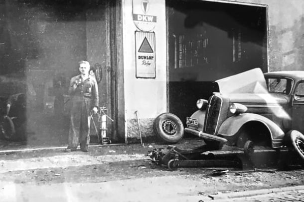 Kfz-Arbeiter steht neben einem Reparatur-Auto